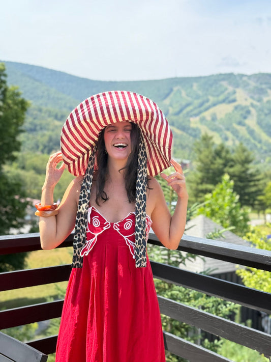 Woman in a red dress and sun hat with mountains in the background